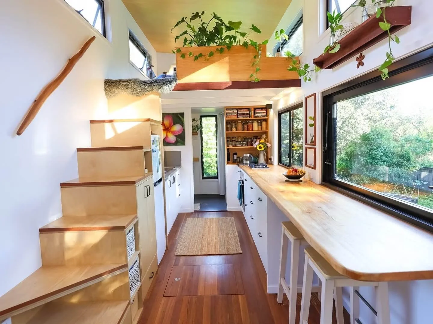 Interior da tiny house com mezzanine, madeira natural e várias janelas